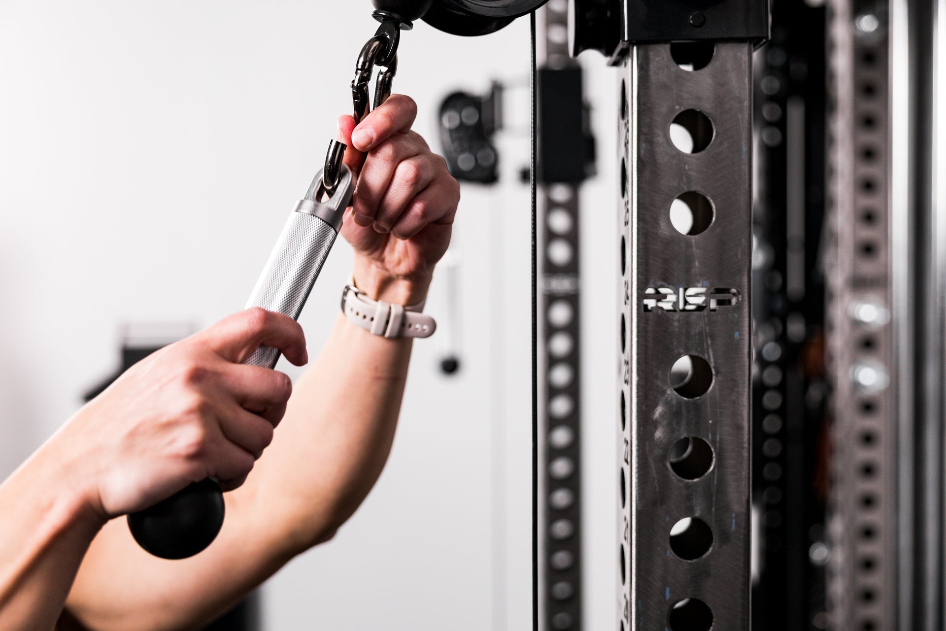 An athlete attaching the REP® x Kleva Built® ISO Pushdown Grip on a REP Ares™ 2.0 cable attachment